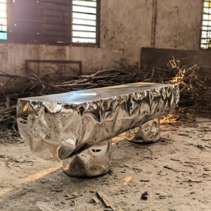 Stainless steel bench shaped as a wooden log in a factory setting.