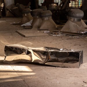 Sculptural bench in stainless steel mirror finish resembling an ancient monolith