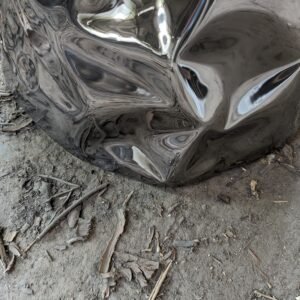 Details of metal sculptural dining table base with sculptural texture in stainless steel in a reflective finish.