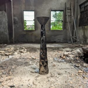 Pedestal in stainless steel with a sculptural texture in a factory setting.