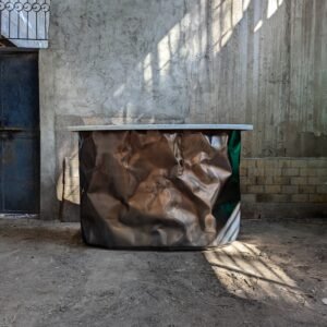 Full view of the Diamante Bar in a rustic indoor setting, showcasing its crumbled matt stainless steel surface and unique sculptural aesthetics.