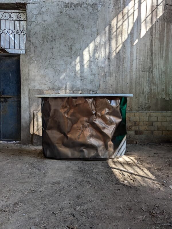 Full view of the Diamante Bar in a rustic indoor setting, showcasing its crumbled matt stainless steel surface and unique sculptural aesthetics.