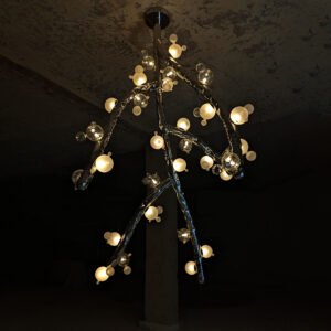 Suspended Molecule Canopy Light shown glowing in a raw-textured industrial setting — sculptural stainless-steel lighting with artful glass spheres