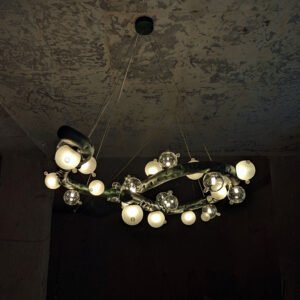 Molecule Lasso Light over round dining table – stainless-steel chandelier with blown-glass globes