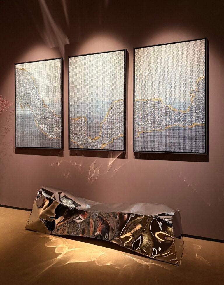 Mirror polished stainless steel sculptural bench against maroon wall in PAD London.